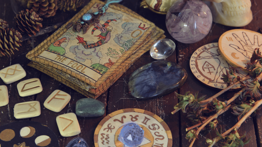 Zestaw narzędzi do praktyk Wicca: runy, kryształy, karty tarota i inne symbole ezoteryczne na drewnianym stole.