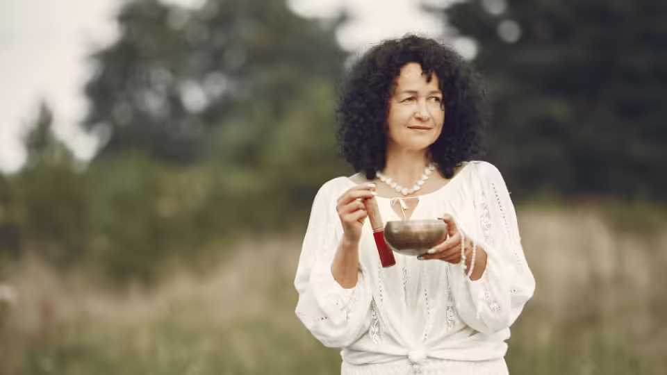 Kobieta trzymająca misę tybetańską na świeżym powietrzu, używaną do medytacji i terapii dźwiękiem, w tym przy częstotliwościach Solfeggio, wspomagających harmonię ciała i umysłu.