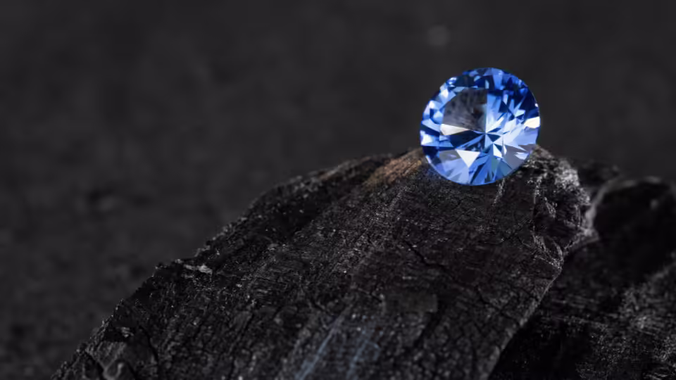 Szafir o głębokim niebieskim kolorze osadzony na ciemnym tle, ukazujący swoje wyjątkowe szlify i blask.