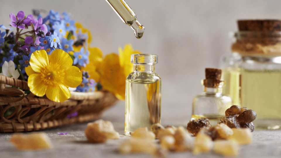  Aromatyczne buteleczki z olejkami eterycznymi, otoczone kwiatami i naturalnymi żywicami, tworzące atmosferę relaksu i natury.