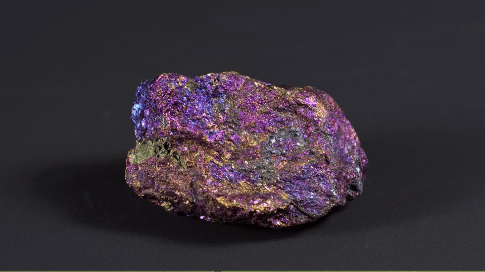Chalkopiryt surowy – kolorowy minerał o fioletowo-złotym połysku na czarnym tle