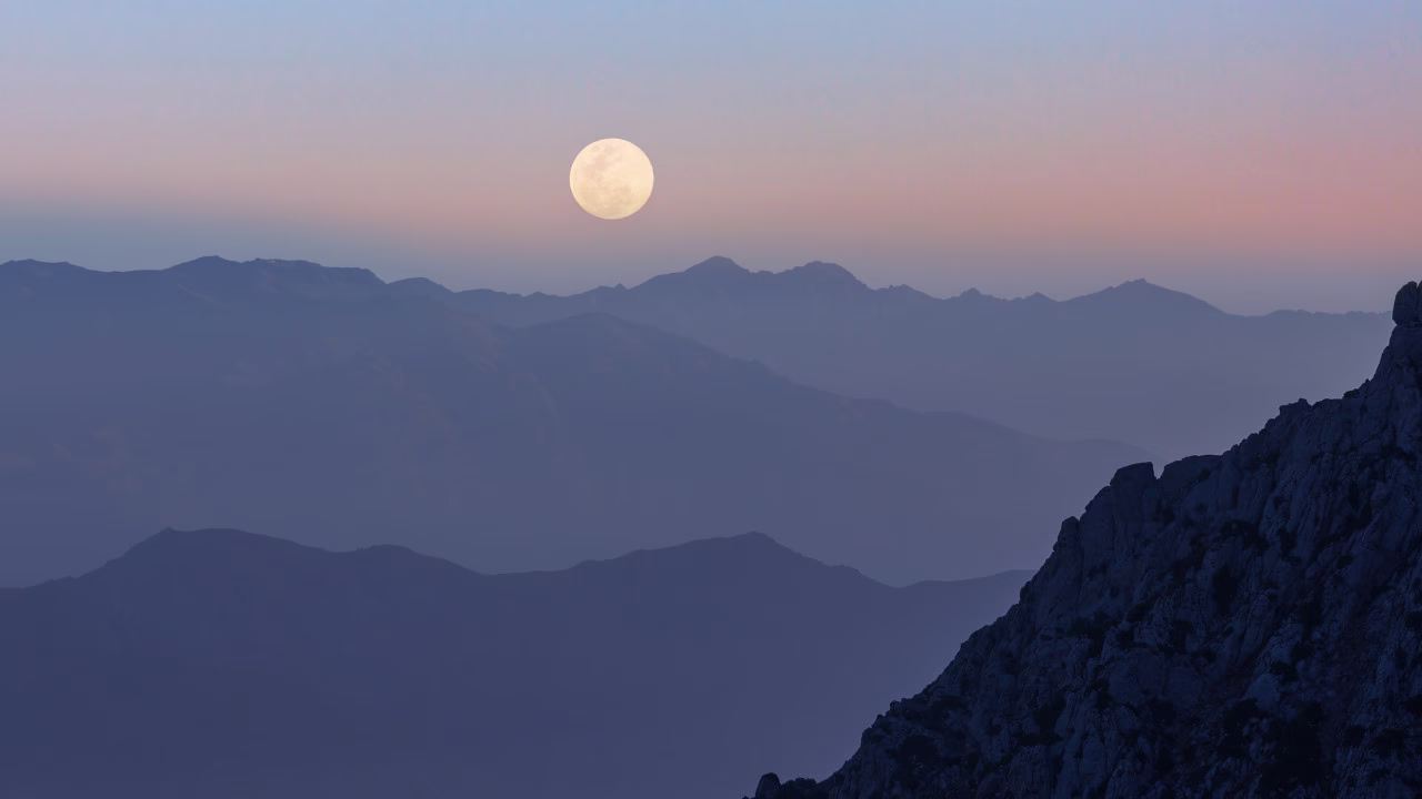 Pełnia Księżyca nad górskim krajobrazem o zmierzchu