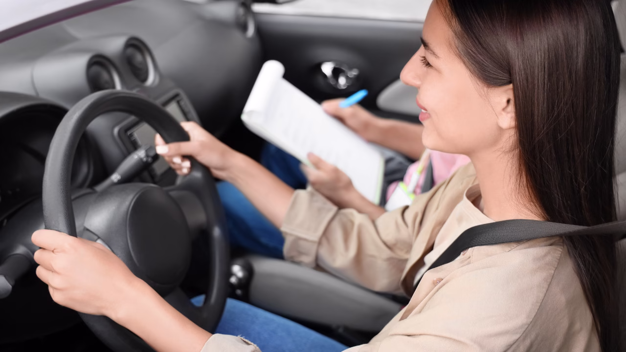 „Kobieta zdająca egzamin na prawo jazdy, trzyma kierownicę podczas jazdy, egzaminator notuje uwagi w arkuszu”