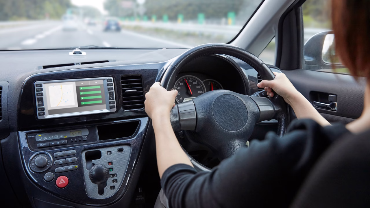 „Widok z miejsca kierowcy podczas jazdy samochodem na drodze, ręce na kierownicy i deska rozdzielcza auta”